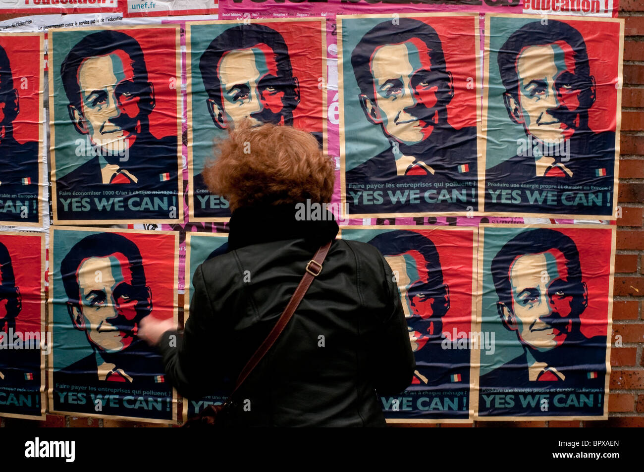 Una donna di fronte una serie di Sarkozy manifesti sui colori della bandiera francese (blu,bianco, rosso), dicendo "Yes We Can". Foto Stock