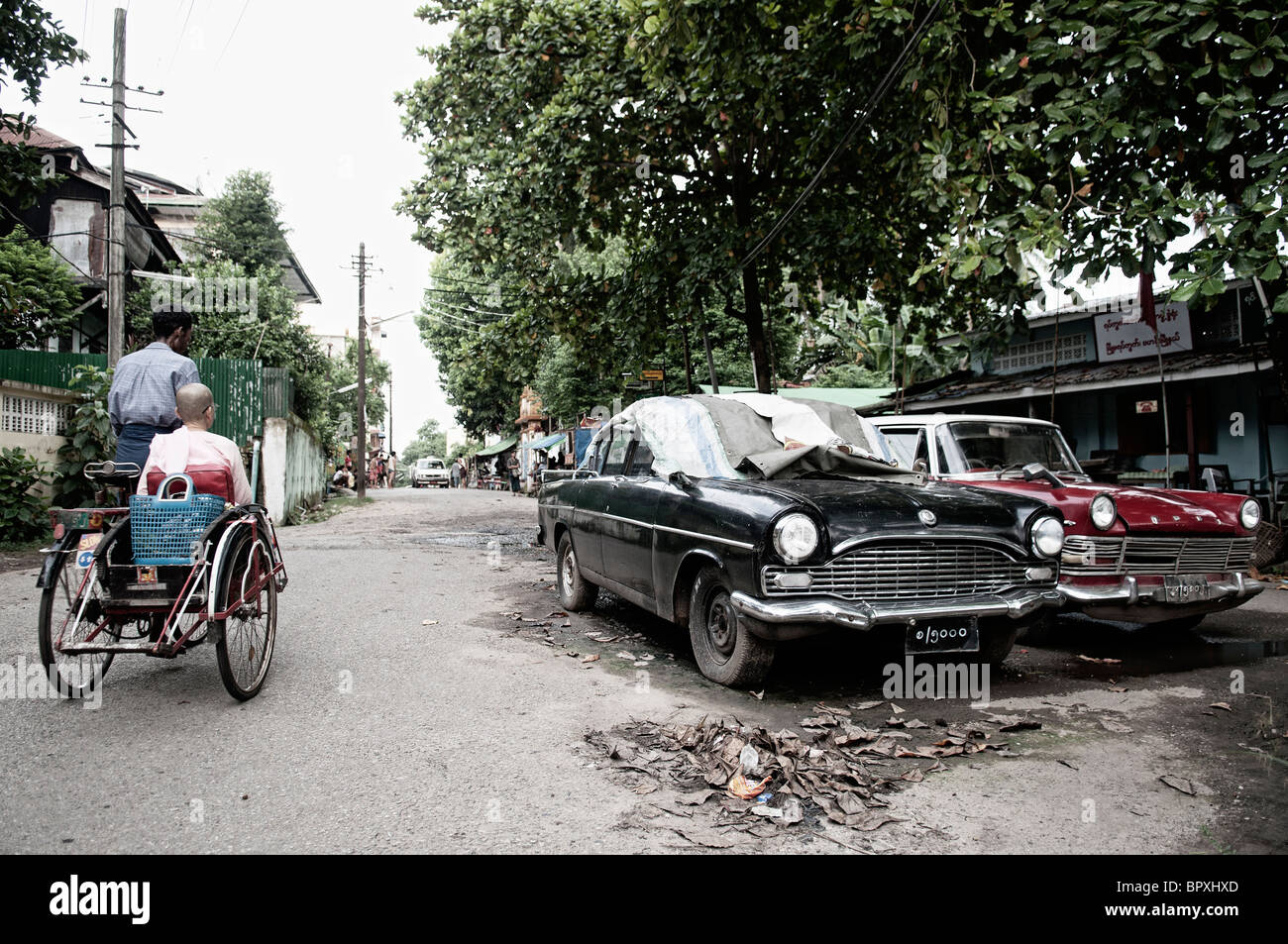 In rickshaw e vecchia auto d'epoca sulla strada Myanmar Birmania Yangon Asia Foto Stock