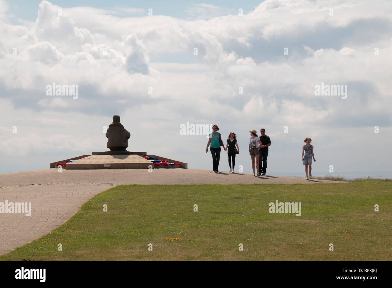 Una famiglia per il Battle of Britain Memorial a Capel le Ferne, Kent, Regno Unito oltrepassando la centrale seduti airman statua. Foto Stock