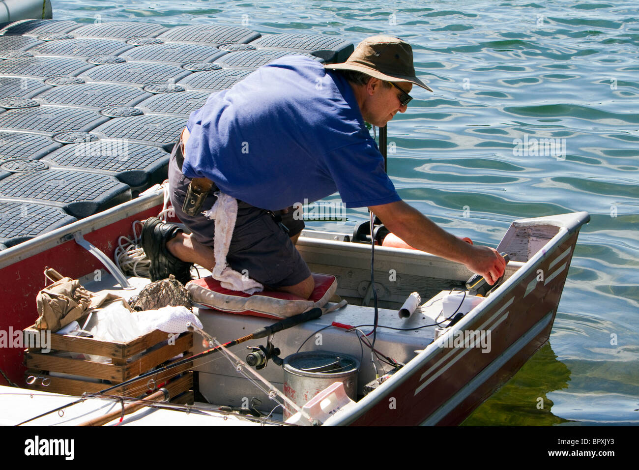 Un pescatore nel retro della sua barca. Tenetevi pronti per una giornata sull'acqua. Foto Stock