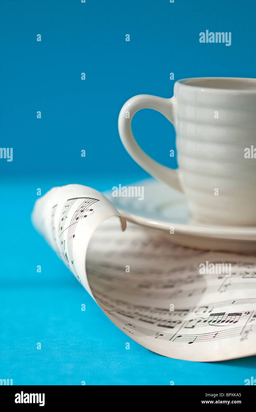 Bianco tazza di caffè si trova nella parte superiore della pagina di arricciatura della musica Foto Stock