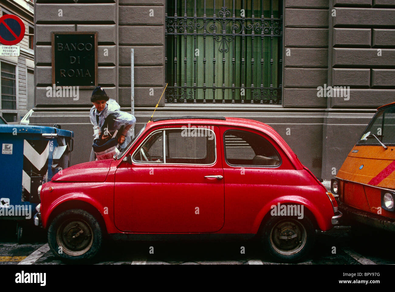 Parcheggio attendant si ferma per controllare il parabrezza (parabrezza) di una Fiat 500 auto in Firenze street. Foto Stock