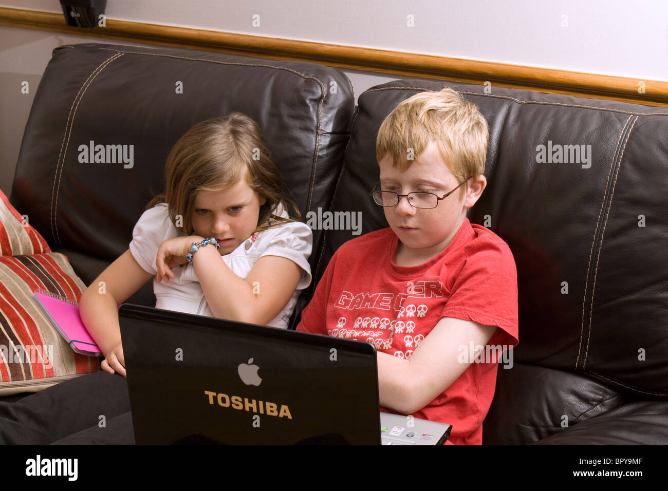 Una bimba di 8 anni, e ragazzo di 11 anni si concentrano su un computer portatile Foto Stock