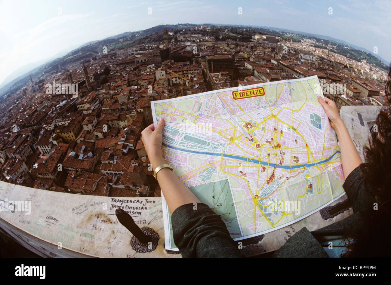 Obiettivo Fisheye vista aerea della città di Firenze come una signora sondaggi il paesaggio urbano utilizzando una mappa turistica. Foto Stock