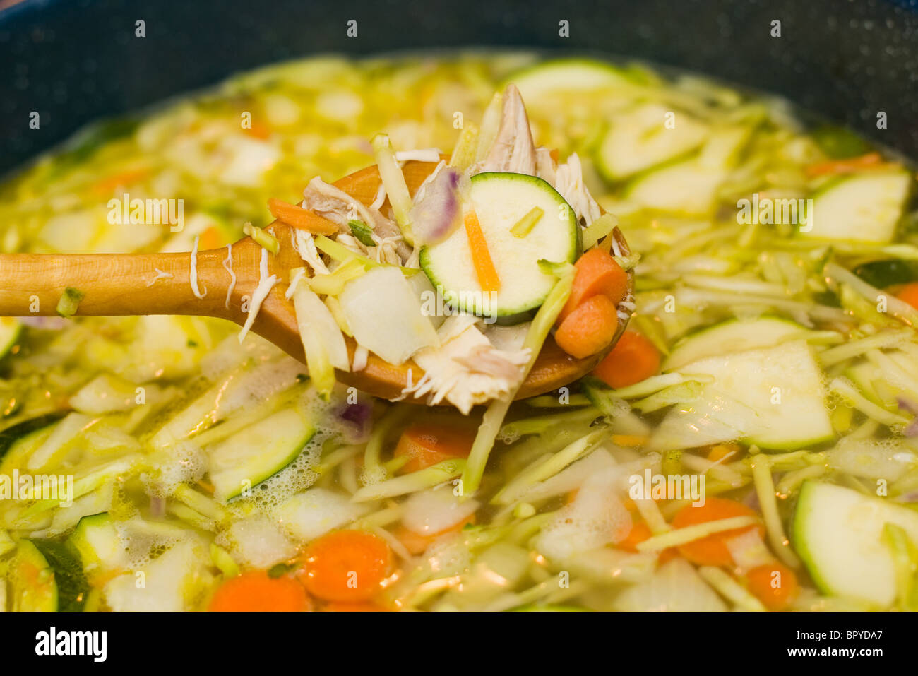 Cucchiaio di legno in una pentola di zuppa. Fase finale nel fare in casa la zuppa di pollo. Foto Stock