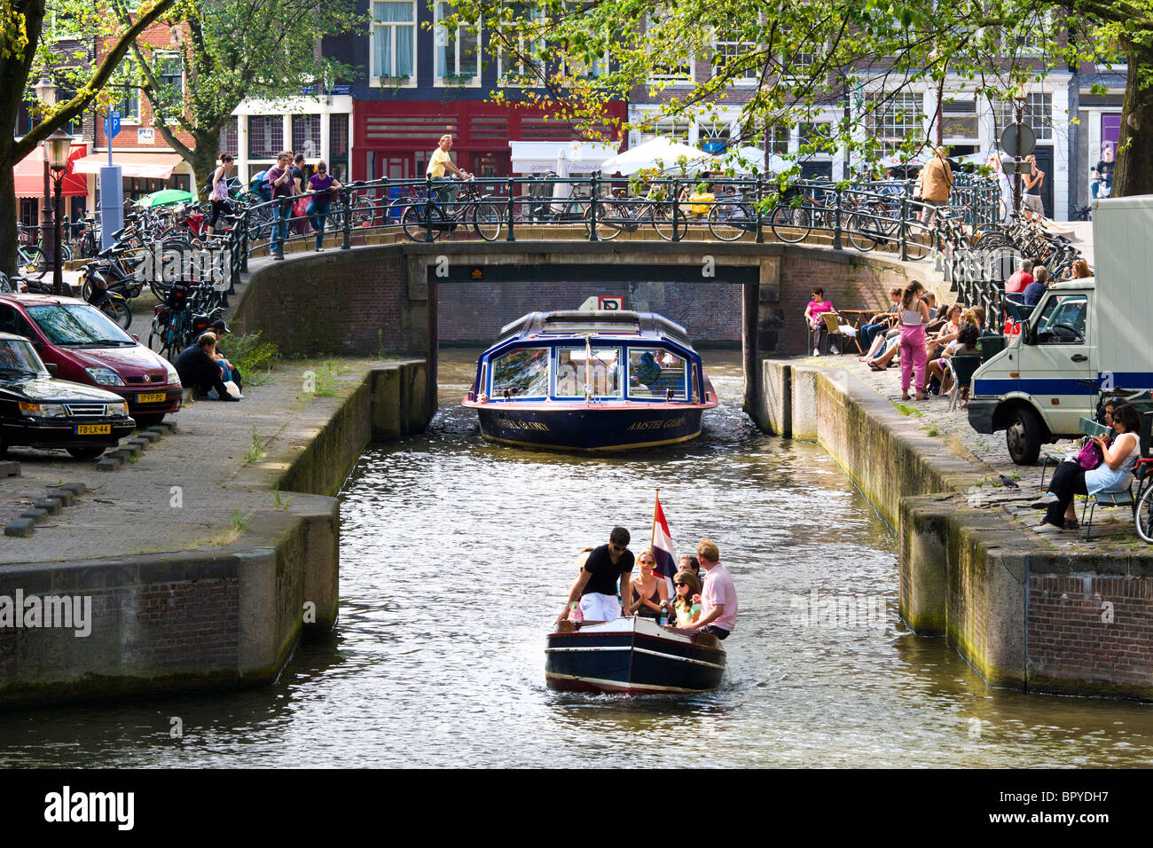 Amsterdam. Canal Cruise tour in barca e piccolo sloop in Leliegracht Canal con caffetterie. Turisti che si siedono e guardare. Foto Stock