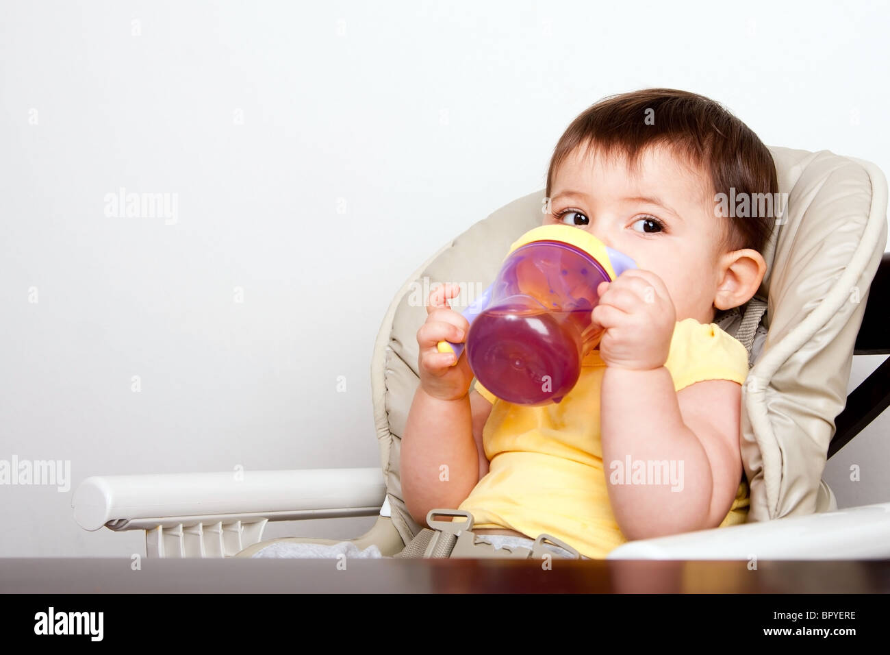 Carino il bambino neonato ragazza ragazzo seduto in poltrona a bere dal  bicchiere sippy Foto stock - Alamy