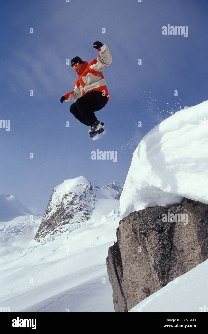 Giovane uomo salta da cilff in neve fresca a Bugaboo Glacier Parco Provinciale, BC, Canada Foto Stock