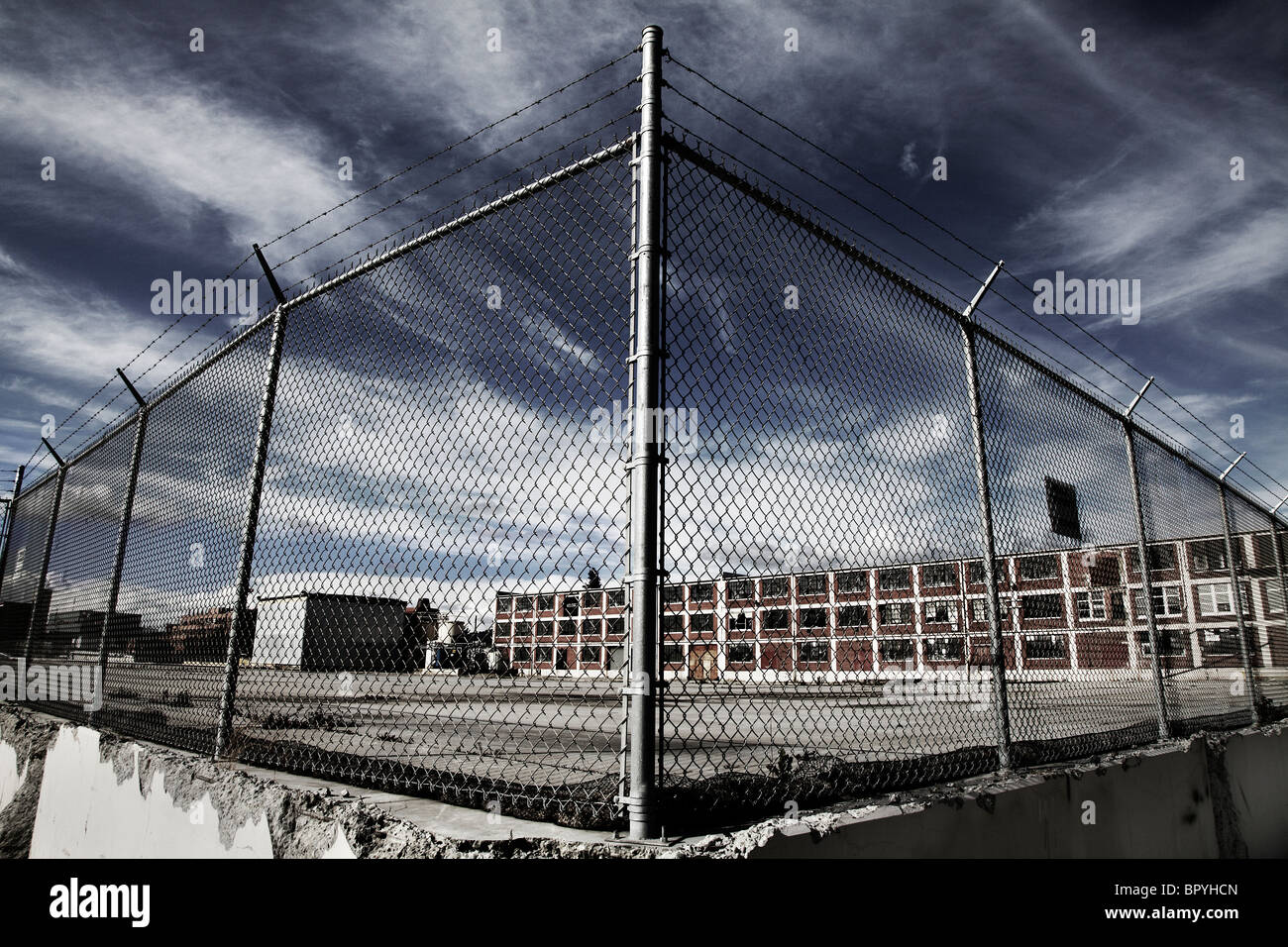Un recinto di fronte ad un edificio in fabbrica con una drammatica del cielo. Foto Stock