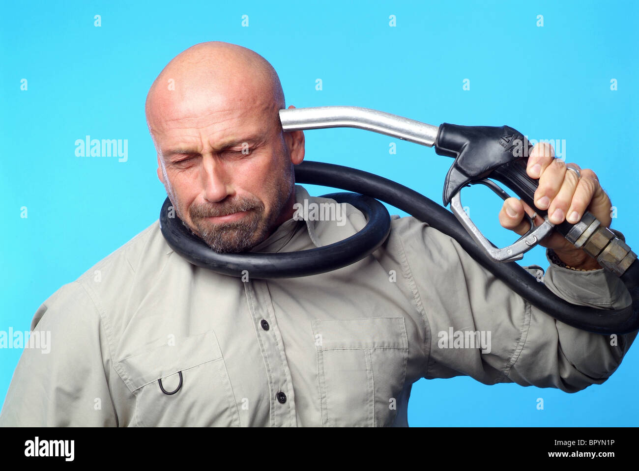 Uomo con un ugello di benzina contro la sua testa Foto Stock