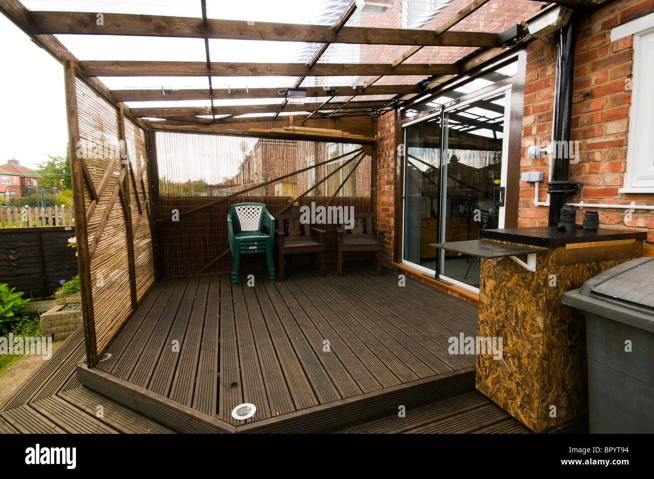Casa costruita patio decking con plastica ondulata per tetti mobili e pannelli di screening in una impostazione interna. Manchester, Regno Unito. Foto Stock