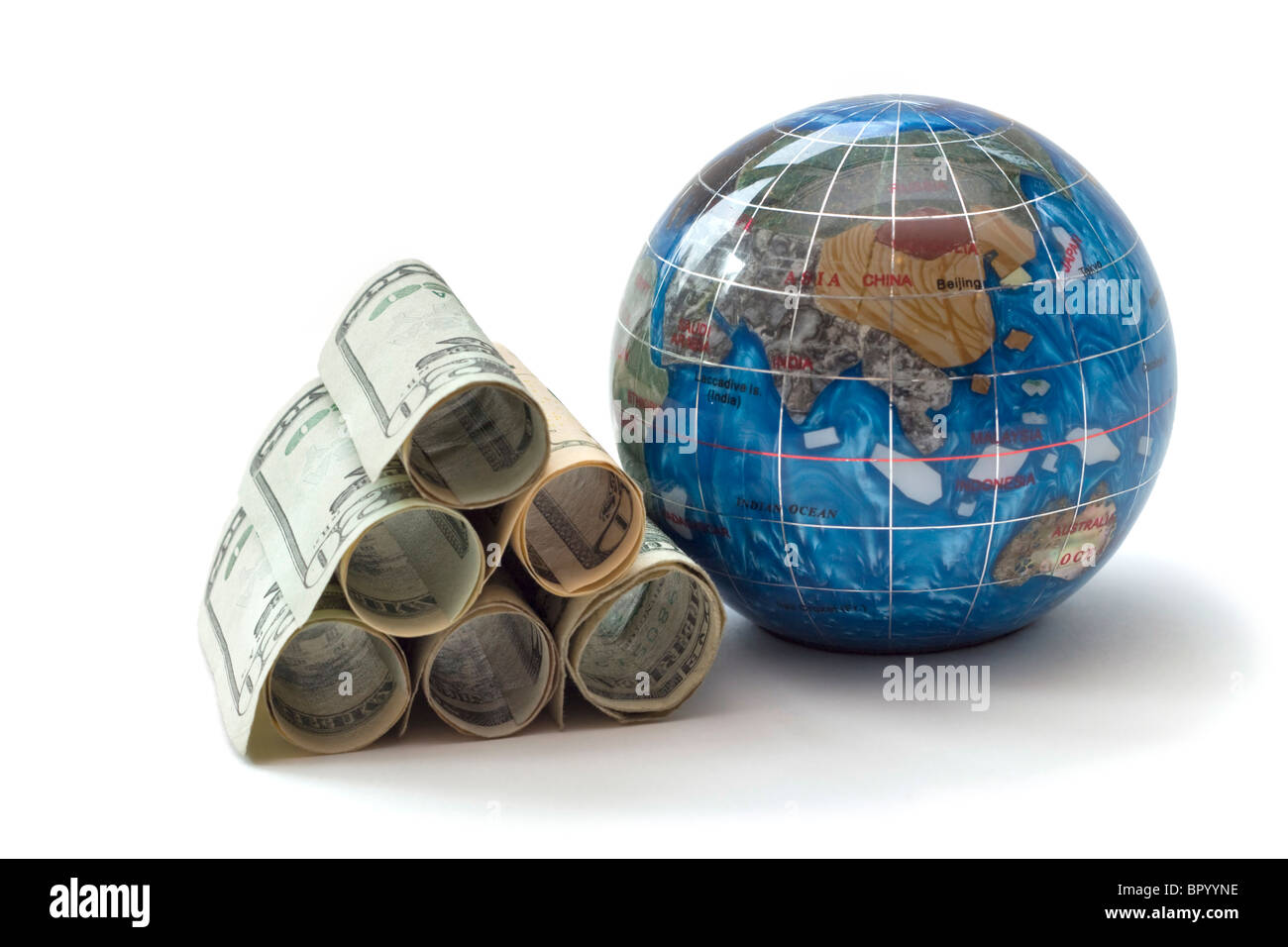 Economia globale rappresentato da un mucchio di dollari laminati impilati accanto a un piccolo globo Foto Stock