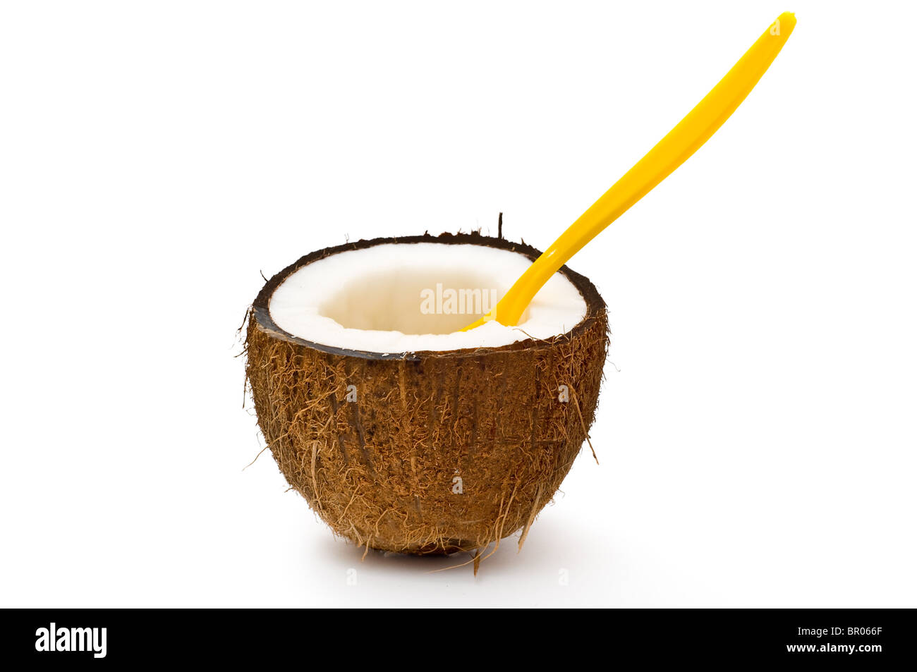 Dimezzato il cocco con cucchiaio arancione isolato su bianco Foto Stock