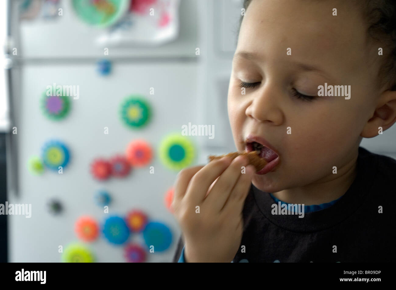 Un ragazzo mangia una pepita di pollo Foto Stock