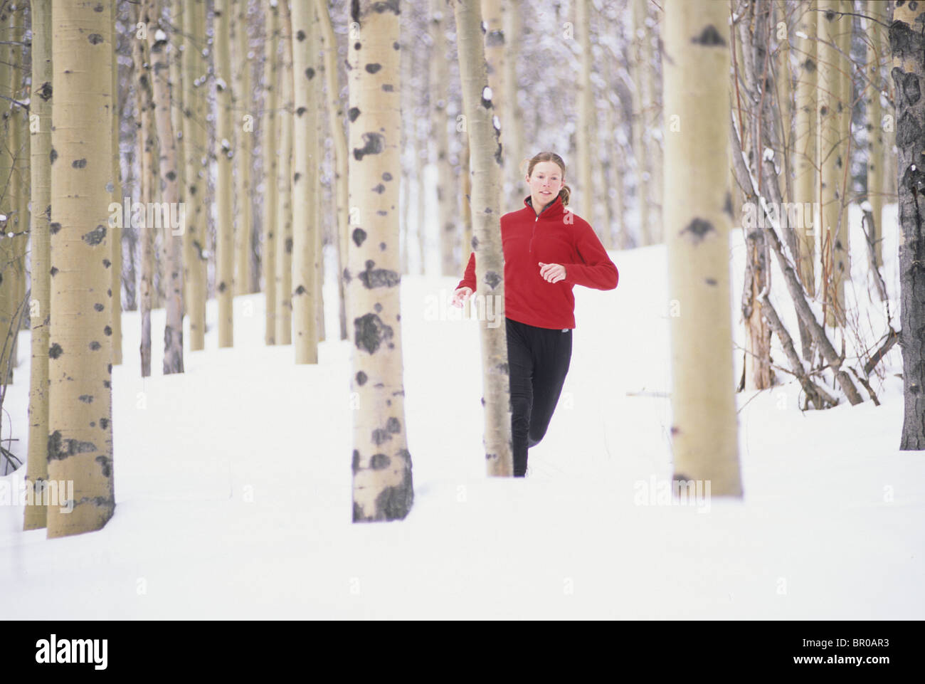 La donna in esecuzione su strade coperte di neve trail. Foto Stock