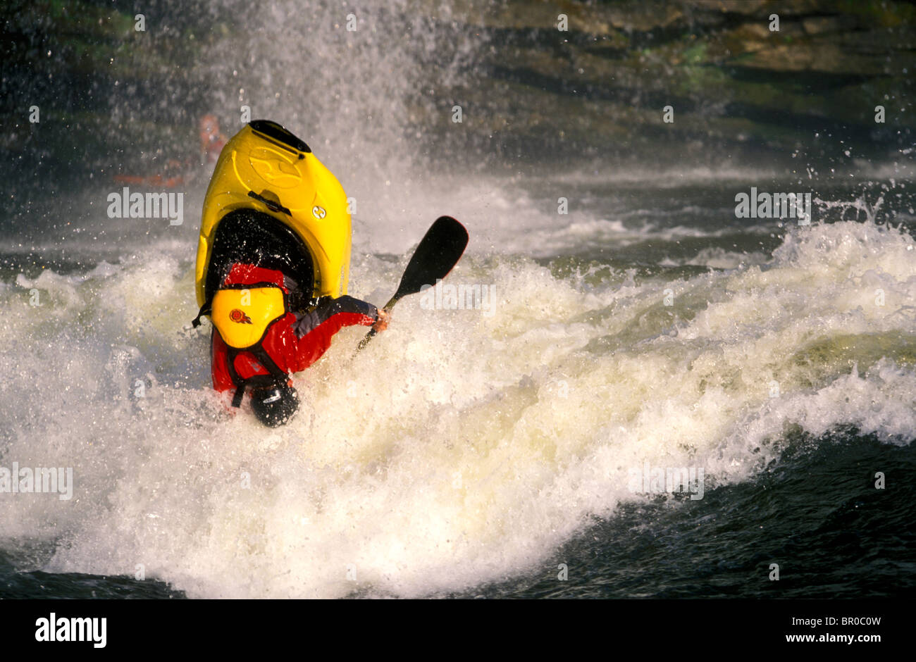 Un uomo flipping capovolta in un kayak in acqua bianca. Foto Stock