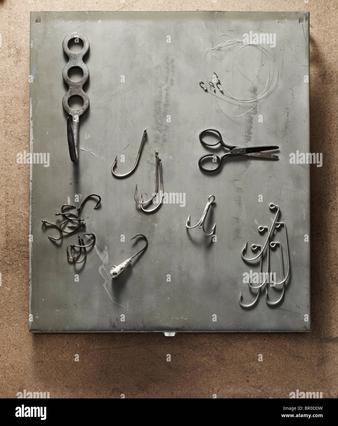 Ganci di pesce e un paio di forbici prevista su un addolorato, grigio Sfondo metallico Foto Stock