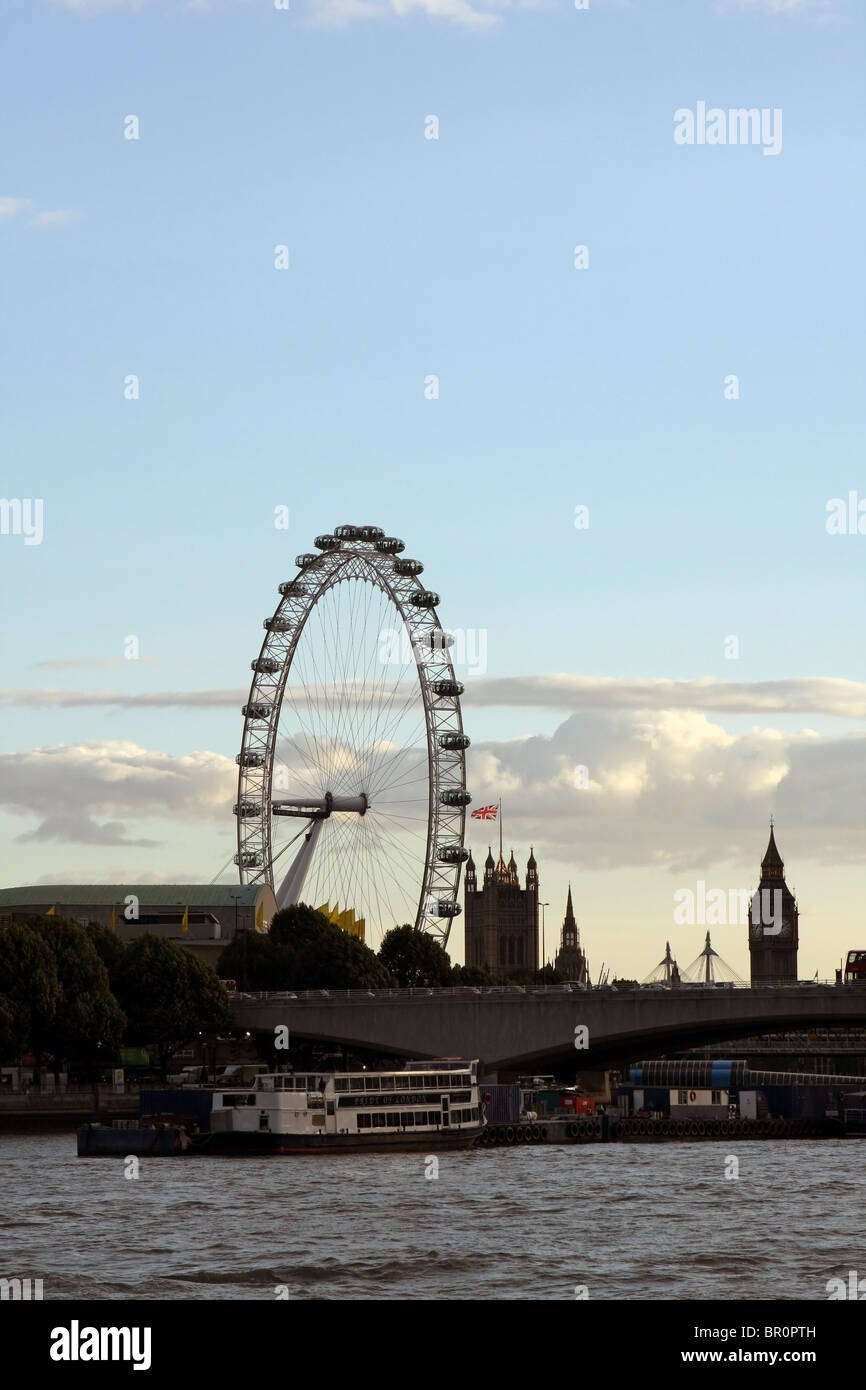 Una vista di parti del London Eye e le case del Parlamento con il fiume Tamigi in primo piano Foto Stock