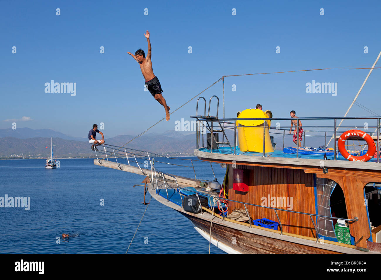 Adolescente salta fuori da una barca durante una gita in barca da Fethiye al 12 isole, bagno turco del Mar Egeo, Turchia Foto Stock