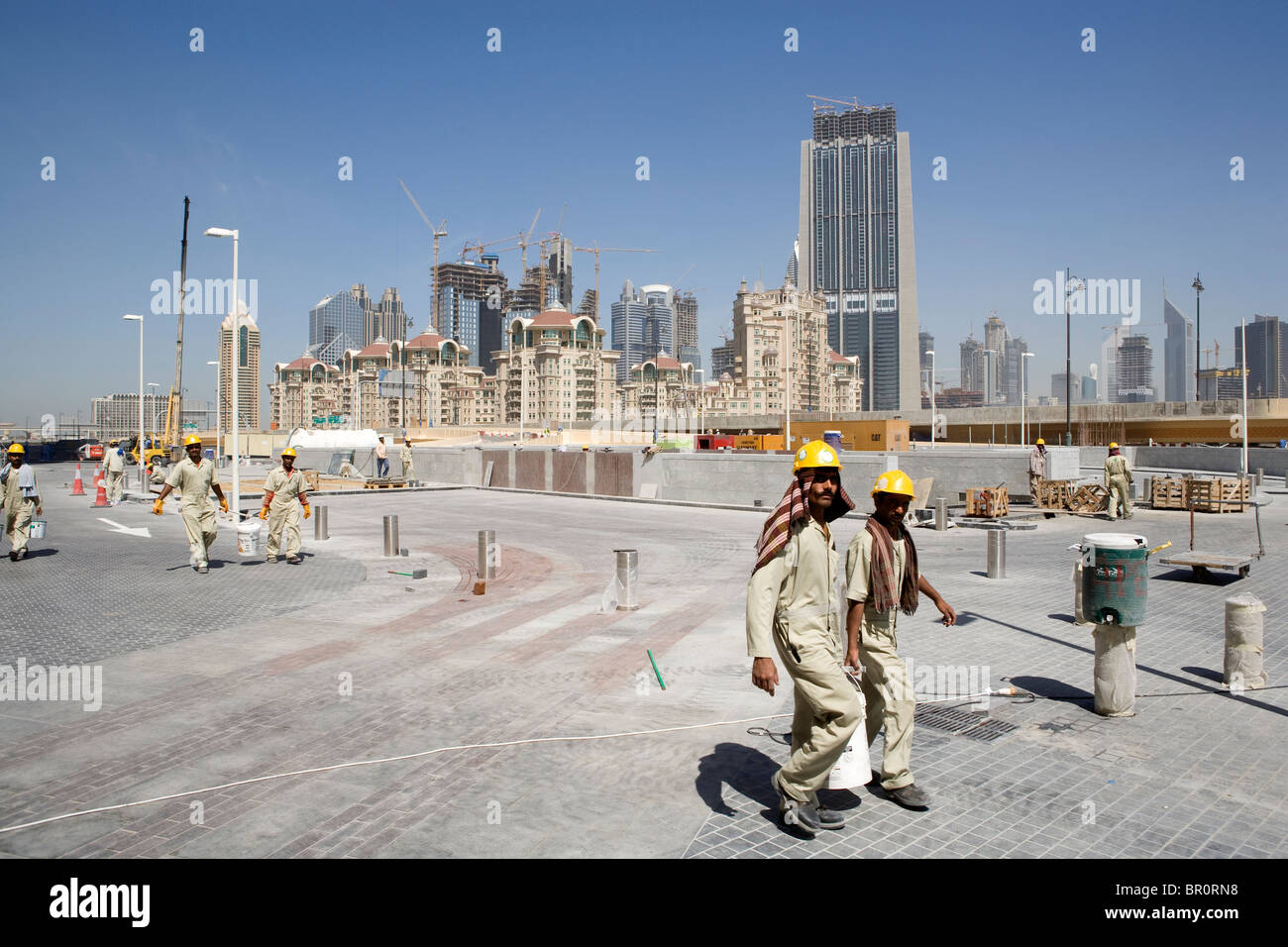 Straniero sono gli uomini che lavorano in siti di costruzione nella parte anteriore del Dubai Mall Shopping Centre di Dubai. Foto Stock