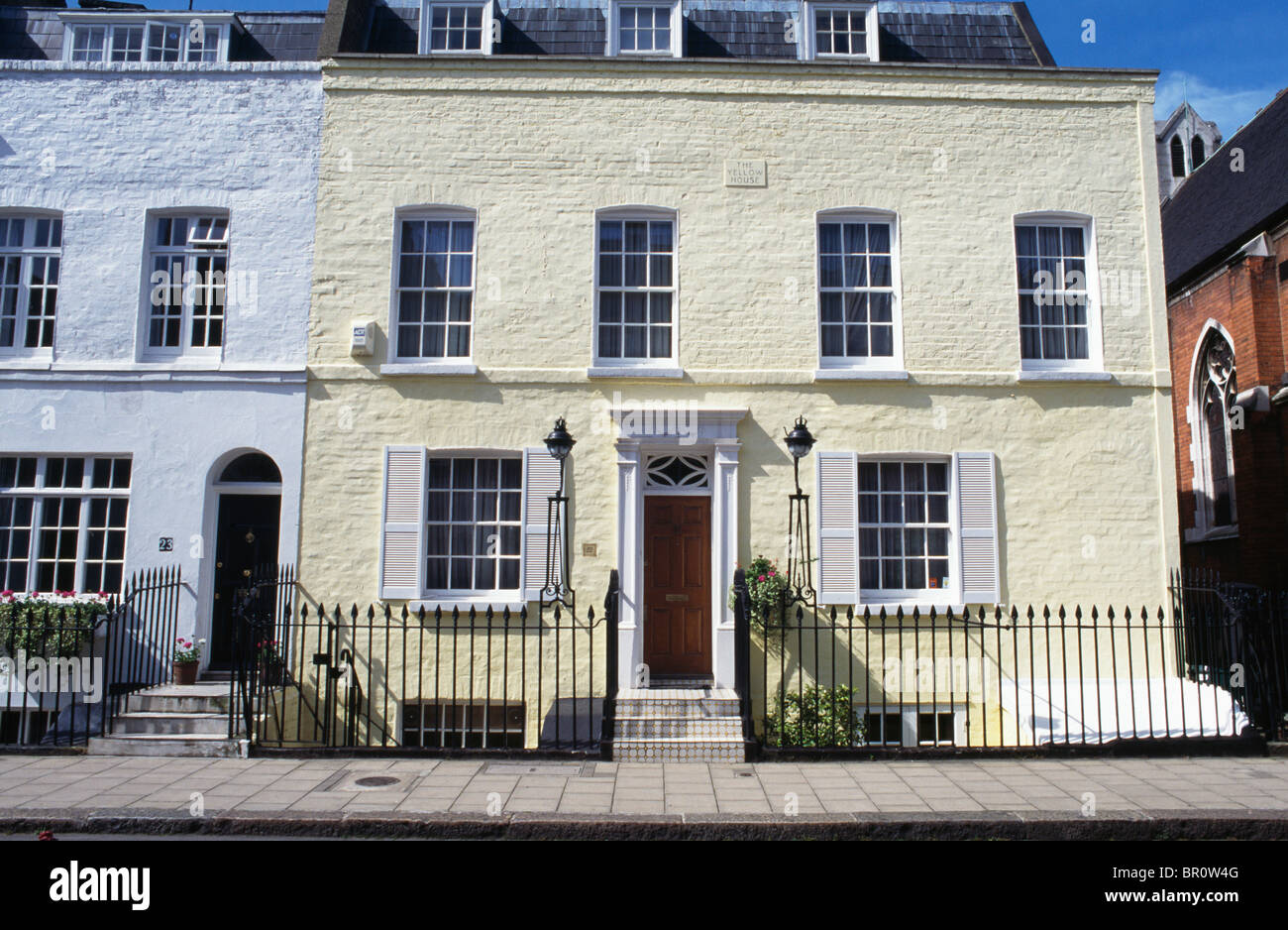 Giallo pallido Vittoriano tradizionale casa a schiera con dipinto di bianco di otturatori a Londra Foto Stock