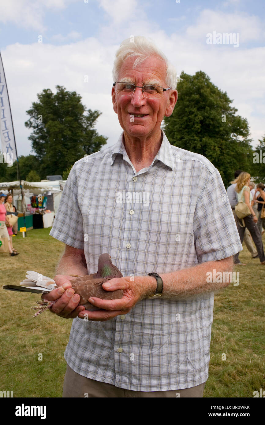 Un vecchio uomo in bicchieri tenendo un piccione. Foto Stock