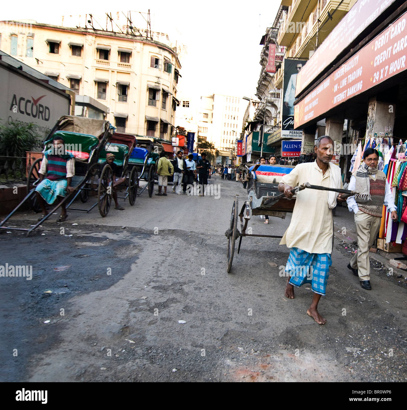 Un uomo tira un rickshaw è una scena comune in Kolkata, India. Foto Stock