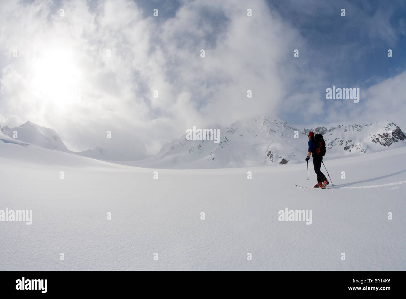 Backcountry rider attraversa il Glacier in tarda giornata cielo tempestoso. (Grandangolo) Foto Stock