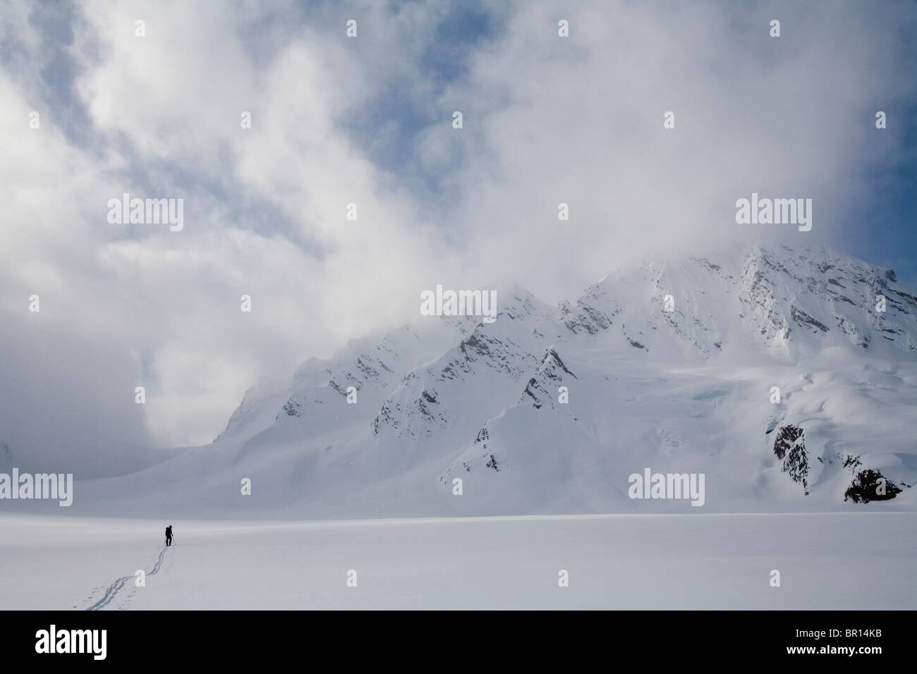 Backcountry rider attraversa il Glacier in tarda giornata cielo tempestoso. Foto Stock
