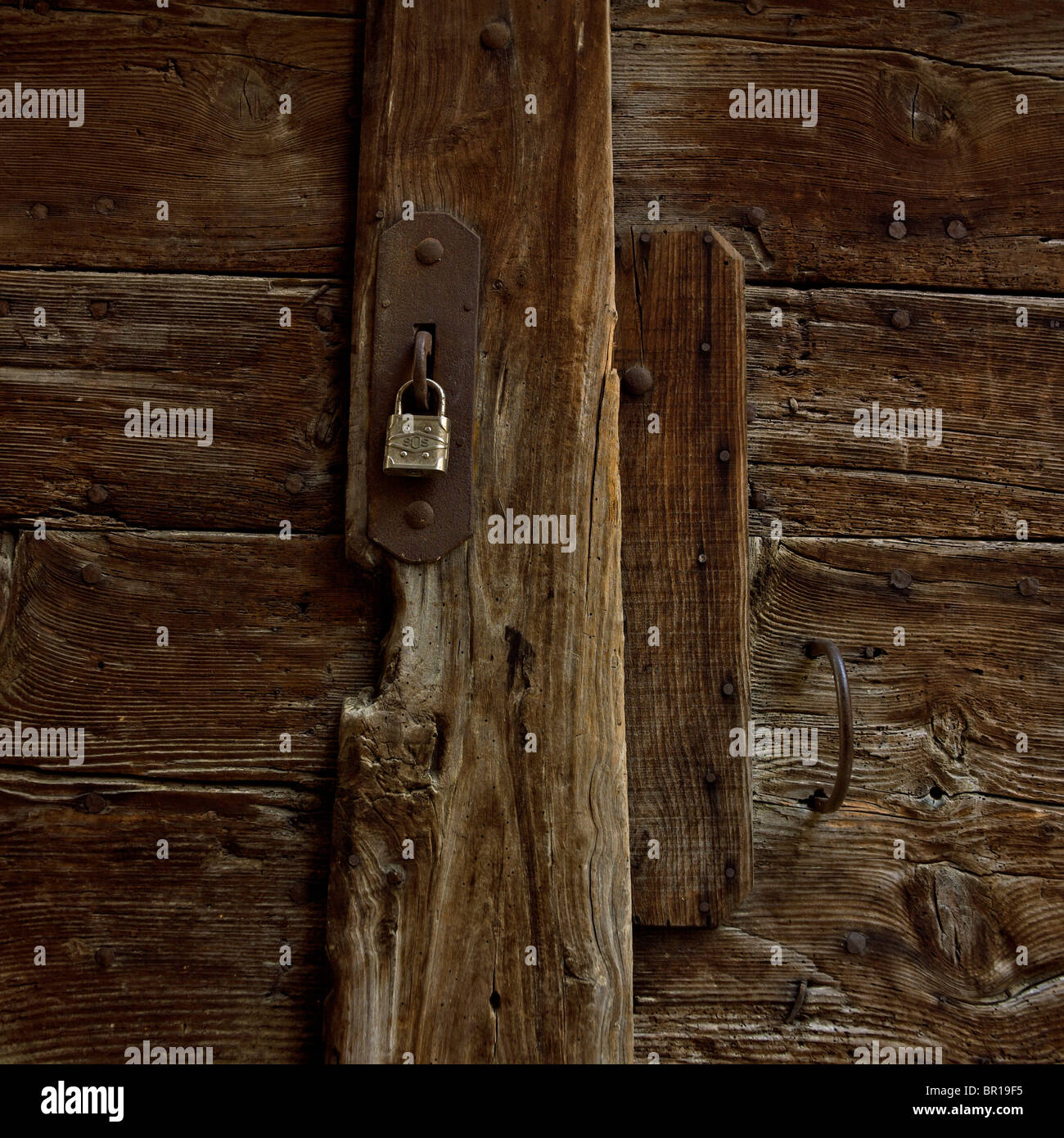 Porta in legno rustico con lucchetto che mostra l'antica maestria artigianale e le texture naturali in un ambiente sereno Foto Stock