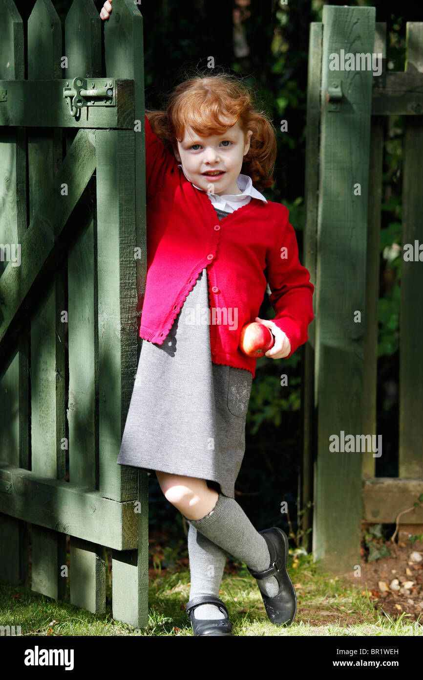 Bambina di 4 anni, indossando la sua uniforme scolastica in un giardino. Foto Stock