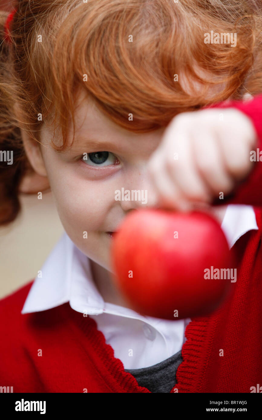 Bambina di 4 anni, indossando la sua uniforme scolastica in un giardino. Foto Stock