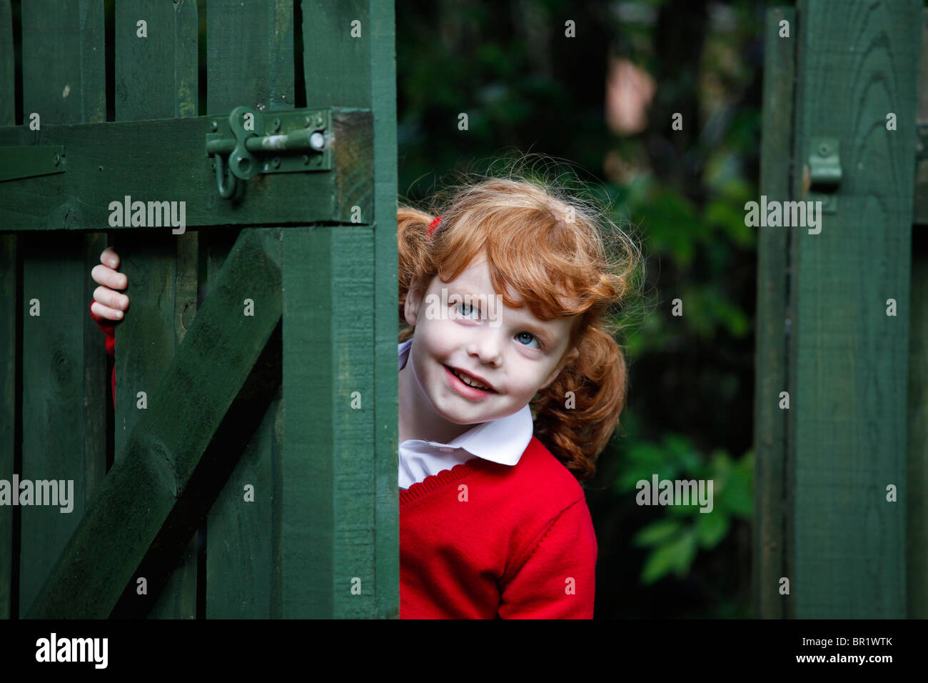 Bambina di 4 anni, indossando la sua uniforme scolastica in un giardino. Foto Stock