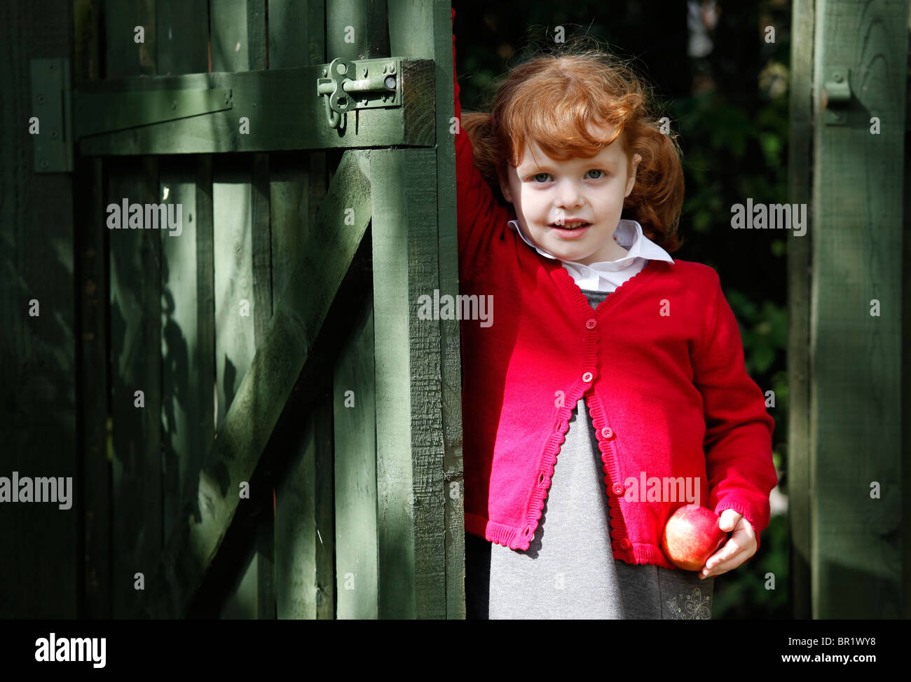 Bambina di 4 anni, indossando la sua uniforme scolastica in un giardino. Foto Stock