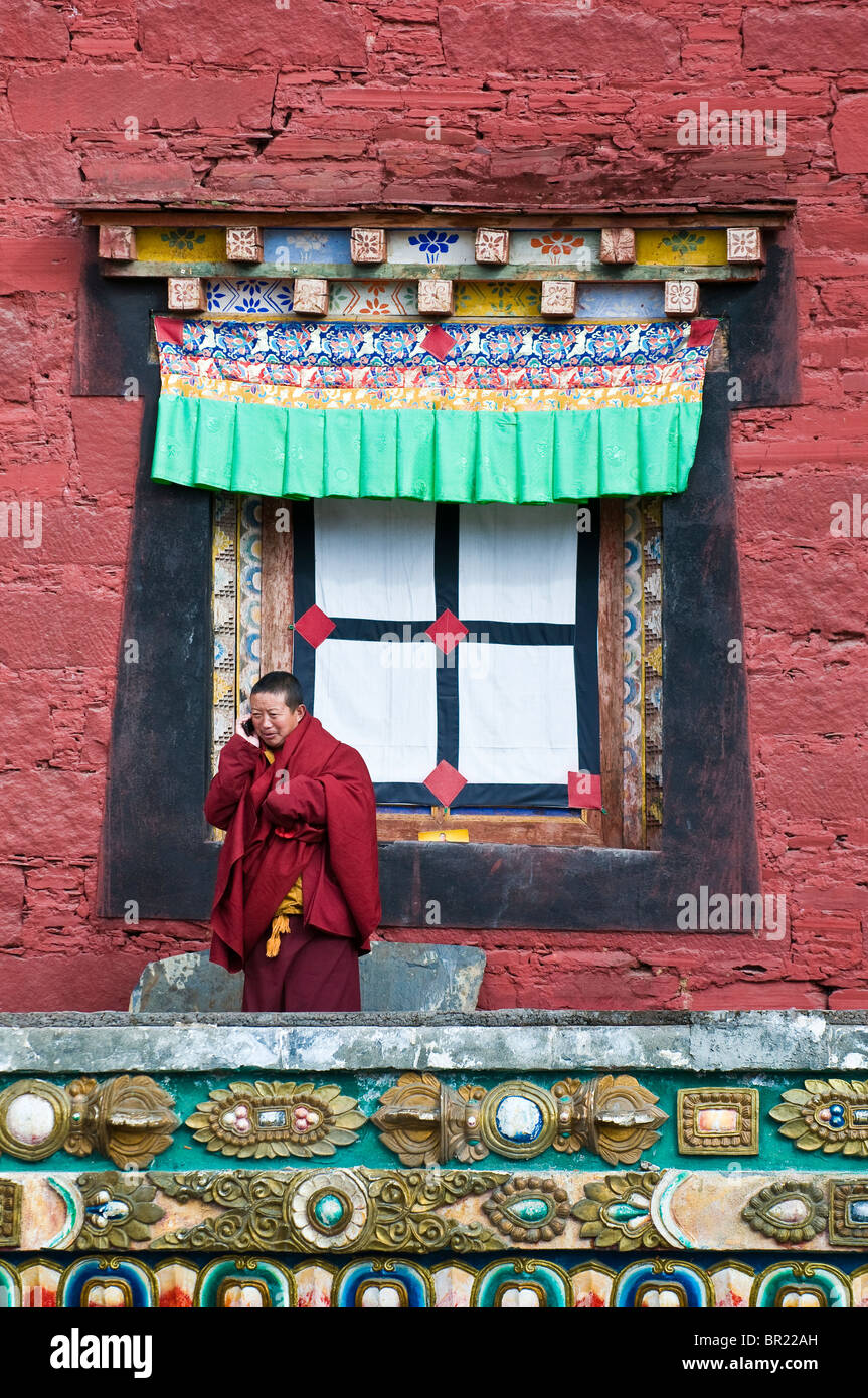 Il Tibetano monaco buddista colloqui sul telefono cellulare al di fuori del tempio principale, Tagong Monastero, nella provincia di Sichuan, in Cina Foto Stock