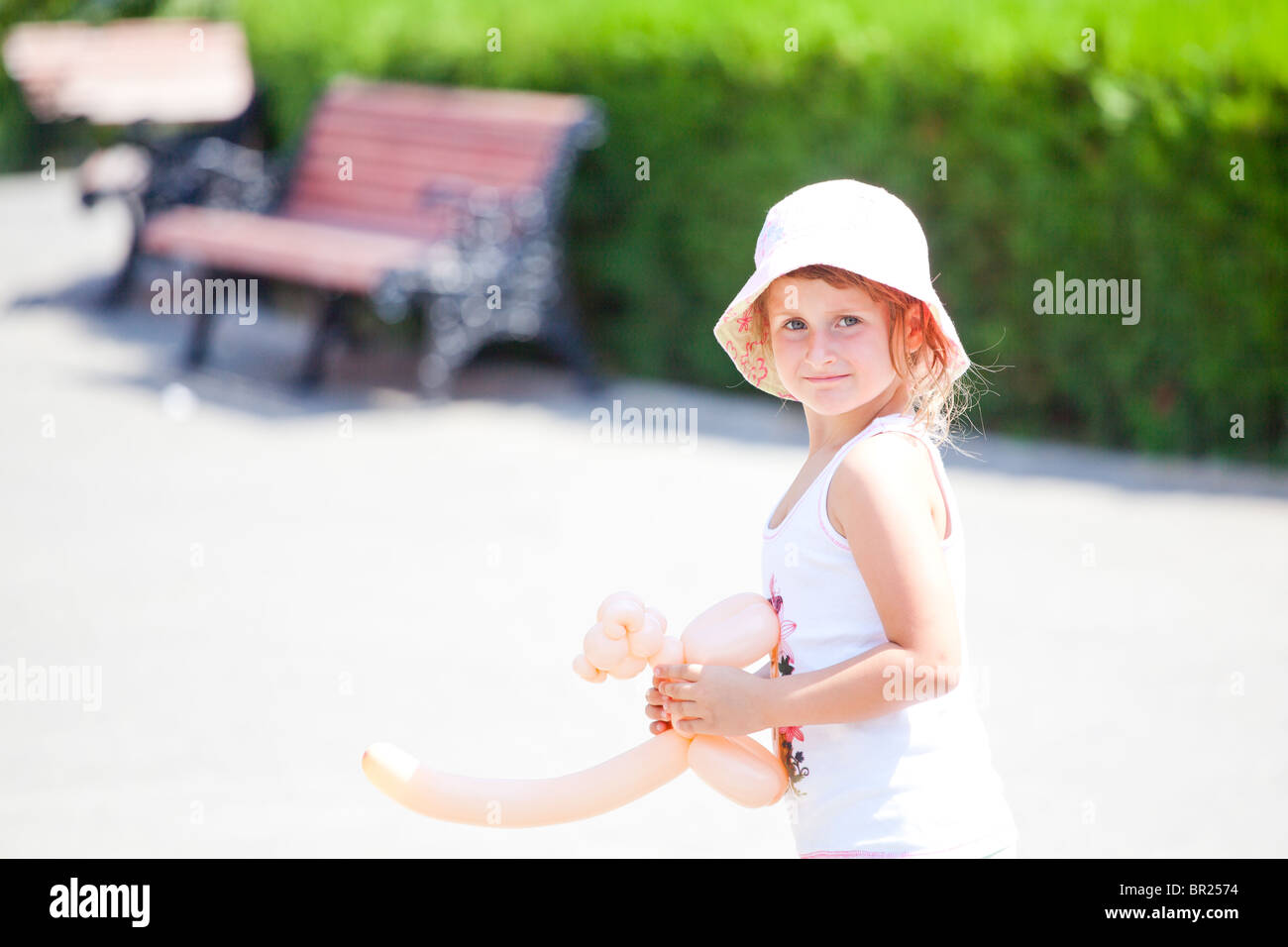 Poco ragazza camminare nel parco in estate tenendo un palloncino giocattolo. Foto Stock