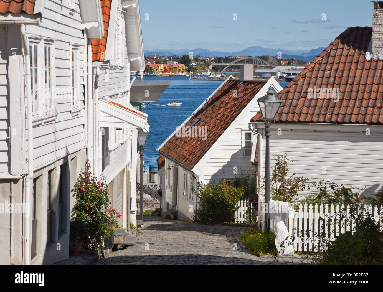 Gamle Stavanger, parte della vecchia città di Stavanger, bianco imbarcati case, power boat nel lontano porto Foto Stock