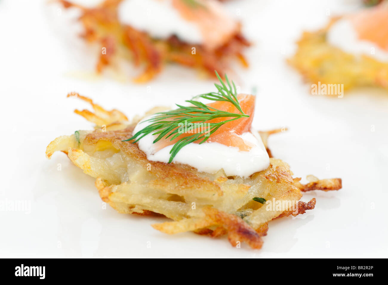 Morso dimensioni röstinchen patate antipasto condito con panna acida fresca, salmone affumicato e aneto. Foto Stock