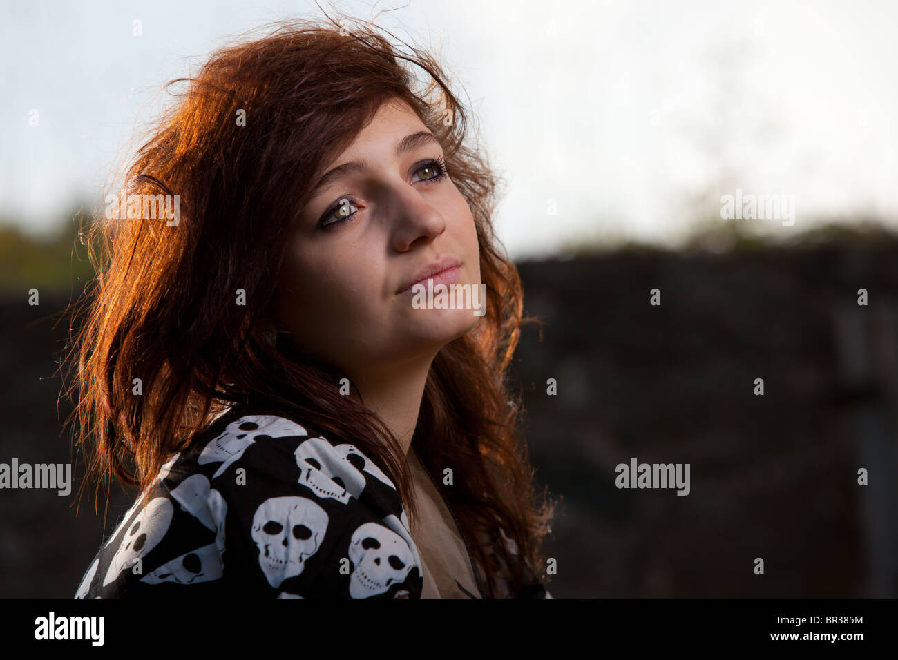 Headshot / Ritratto di un attraente dai capelli scuri giovane donna con la luce del sole sui suoi capelli Foto Stock