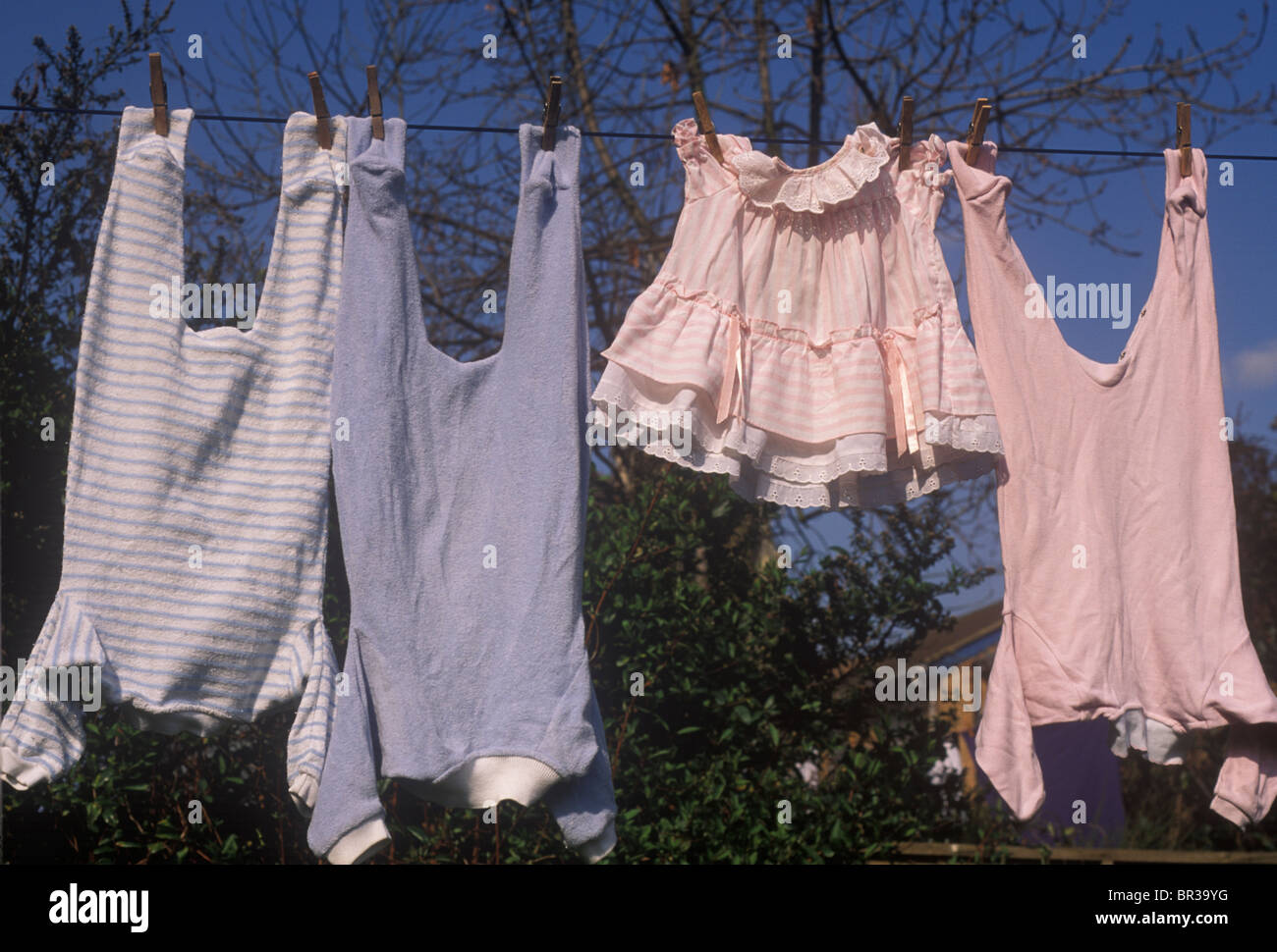 Baby vestiti appesi sulla linea - blu per ragazzi e rosa per le bambine Foto Stock