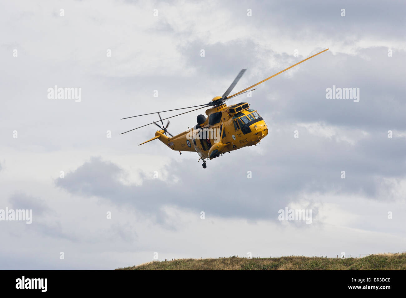 Un giallo, RAF rescue Sea King elicottero vola, oltre Staithes, North Yorkshire, Inghilterra. Foto Stock