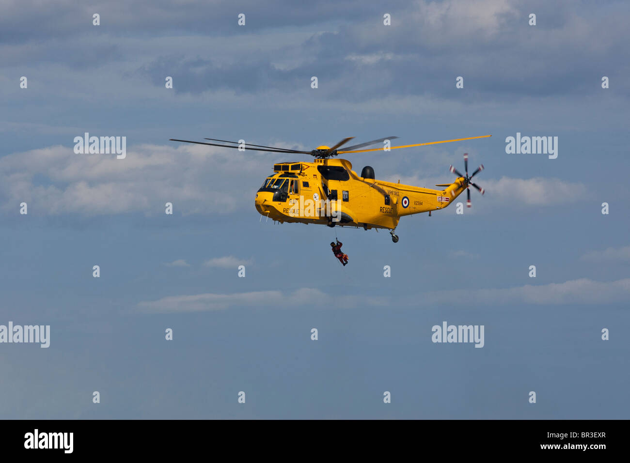 RAF Sea King Salvataggio in elicottero, abbassa una winchman in attesa di costiera RNLI scialuppa di salvataggio. Foto Stock