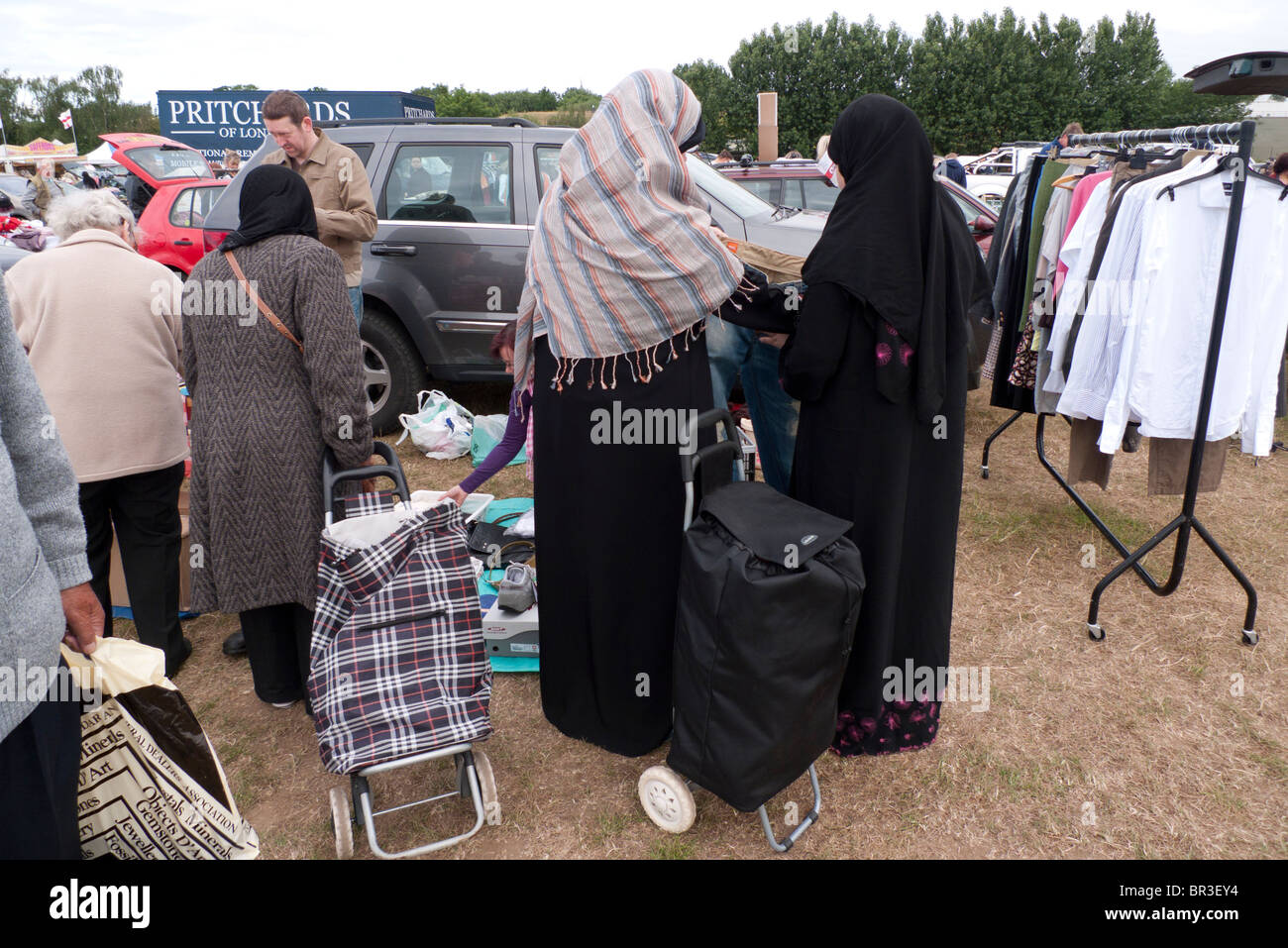 Vestiti in vendita sul tavolo al bagagliaio della vettura in vendita in Surrey, Inghilterra, esaminato dal burkha musulmano donne placcati Foto Stock