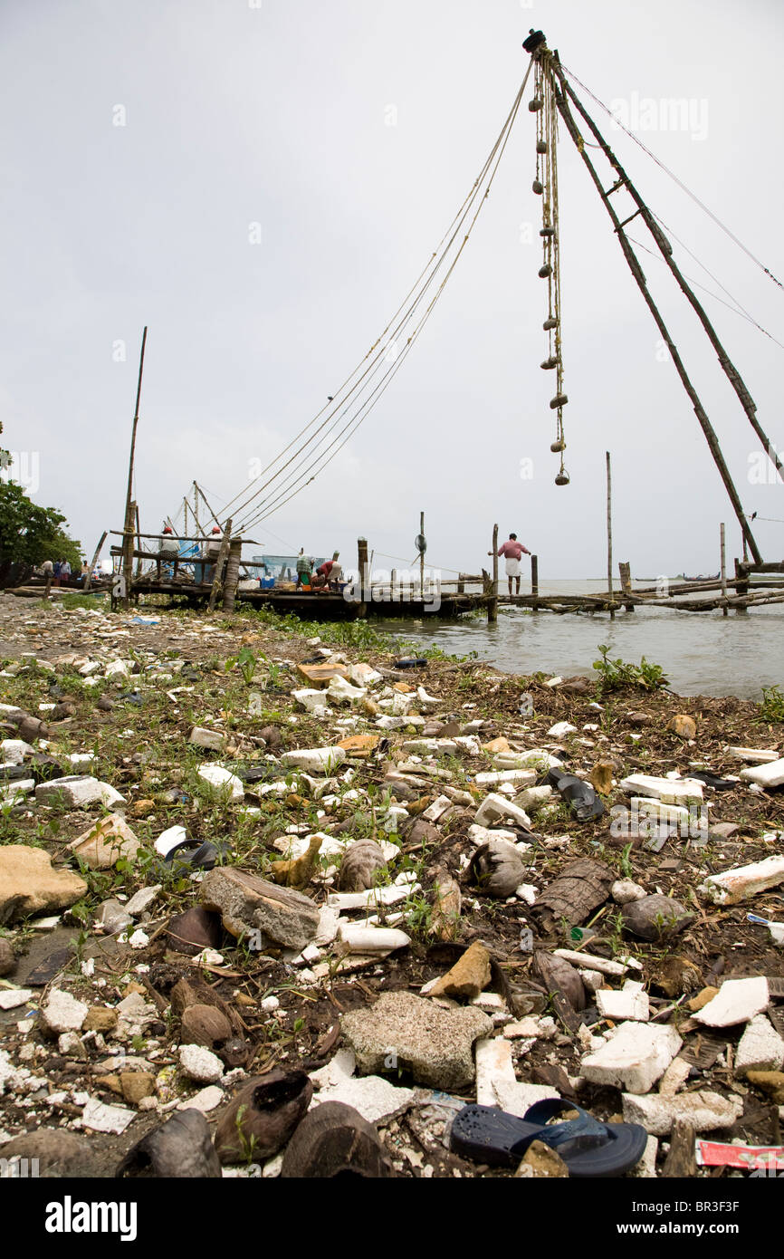 Immondizia disseminata waterfront con reti da pesca in background. Foto Stock