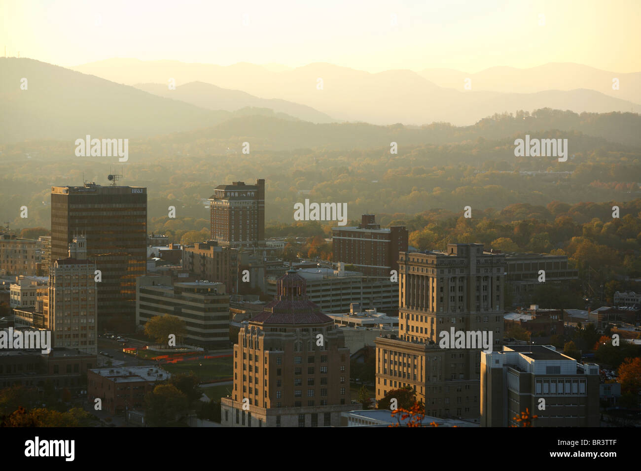 Vista del sole serale impostazione oltre le Blue Ridge Mountains che circondano il centro di Asheville, NC Foto Stock