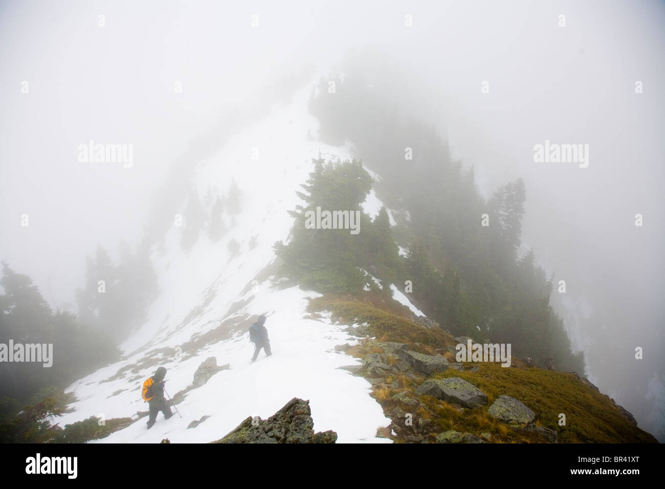 Due alpinisti escursione lungo il crinale dopo aver raggiunto il vertice di un picco nella cascate montagne. Foto Stock