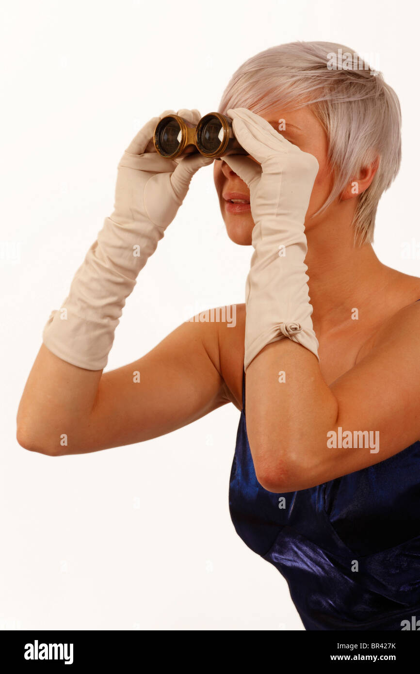 Giovane donna guardando attraverso alcuni bicchieri di opera, una notte fuori all'opera Foto Stock