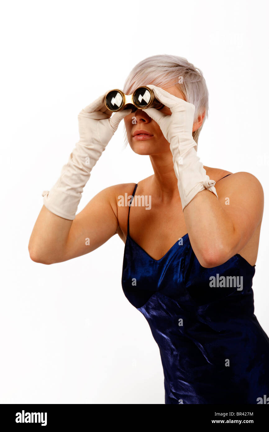 Giovane donna guardando attraverso alcuni bicchieri di opera, una notte fuori all'opera Foto Stock