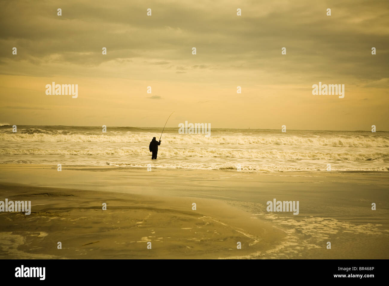 Un uomo solitario pesci nell'Oceano Atlantico, Wildwood, New Jersey. Foto Stock