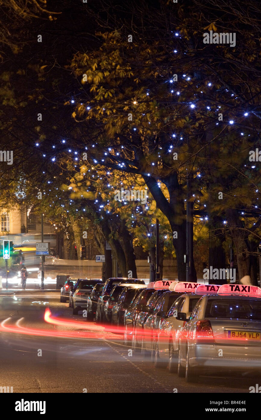 Una stazione di taxi di notte con le luci di Natale, Cheltenham, Gloucestershire, Regno Unito Foto Stock